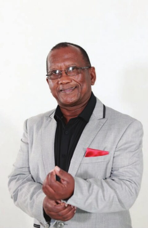 Portrait of Pastor Abraham Manuel in a grey jacket with a red pocket square